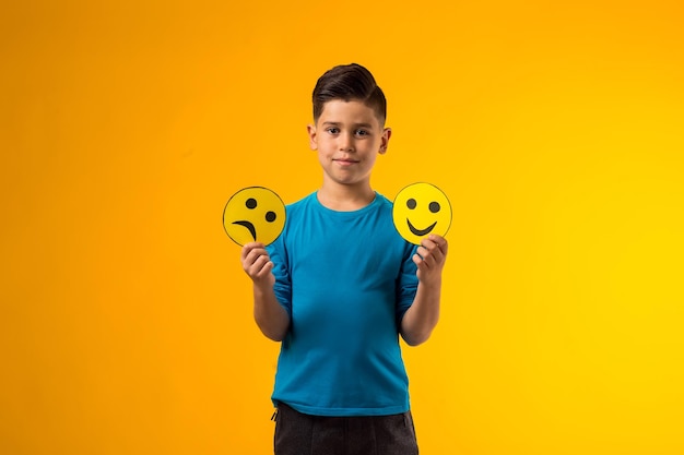 Kindje houdt emoticons vast met gelukkige en droevige emoties
