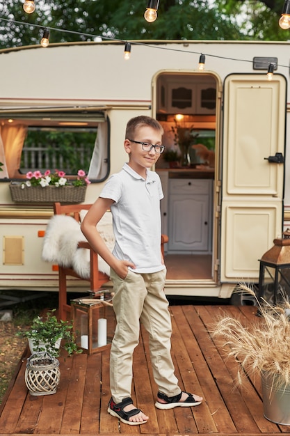 Kindjongen dichtbij een caravan in de zomer bij zonsondergang