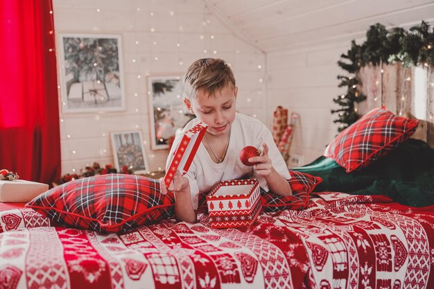 Kindjongen die kerstboom thuis verfraait. Gezin met kinderen vieren wintervakantie. Kinderen versieren woonkamer en open haard voor Kerstmis. Slaapkamer nieuwjaar decor