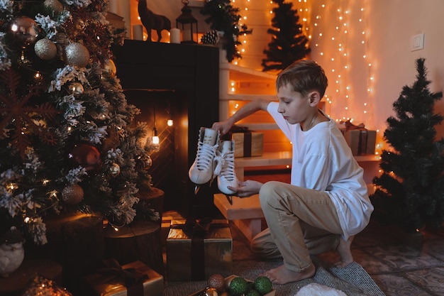 Kindjongen die kerstboom thuis verfraait. gezin met kinderen vieren wintervakantie. kinderen versieren woonkamer en open haard voor kerstmis.