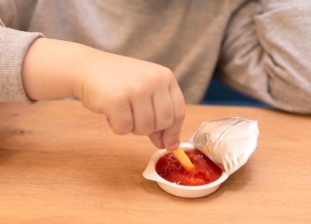 Kindjongen die zijn frietjes met ketchup eet in het café Junkfood ongezond eetconcept