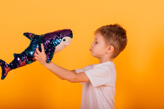 Kindjongen in gele studio met speelgoed vishaai speelgoed