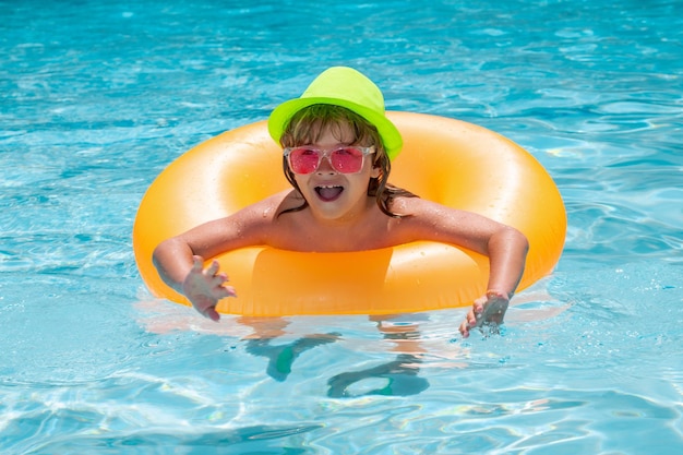 Kindjongen in zwembad met opblaasbare speelgoedring Kinderen zwemmen op zomervakantie Zwemmen voor kind op vlotter Strand, zee en waterpret