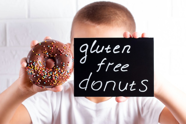 Kindjongen met glutenvrije gezonde chocoladedoughnut. Jong geitje met doughnut. Glutenvrij, sojavrij, lactosevrij product