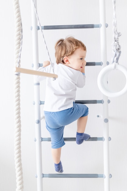 Kindjongen op de Zweedse muur of sportcomplex klimt thuis, het concept van kindersport