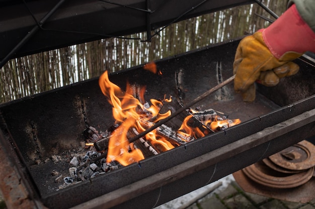 Kindling a fire in the grill turning over burning coals for a barbecue