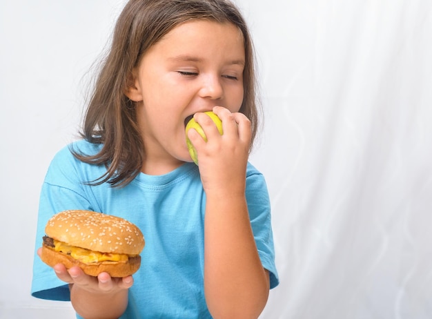 Kindmeisje dat een appel bijt in plaats van een hamburger Gezonde voeding