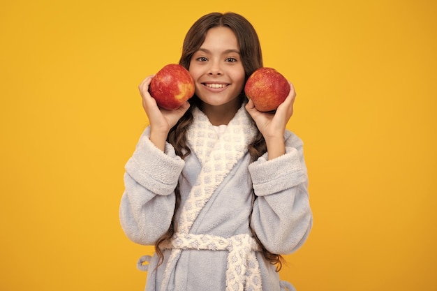 Kindmeisje dat een appel eet over geïsoleerde gele achtergrond Tennager met fruit