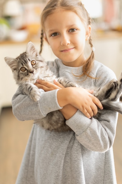 Kindmeisje dat een pluizig katje in haar armen houdt