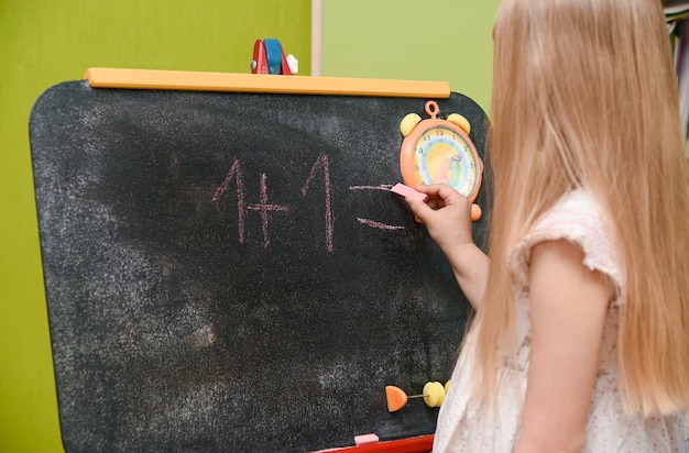 Kindmeisje dat thuis op tekentafel leert schrijven.