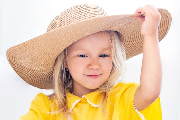 Kindmeisje in een strohoed in gele kleren, de zomerfoto. op een witte achtergrond