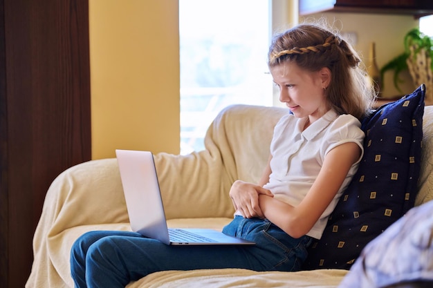 Kindmeisje thuis op de bank met laptop