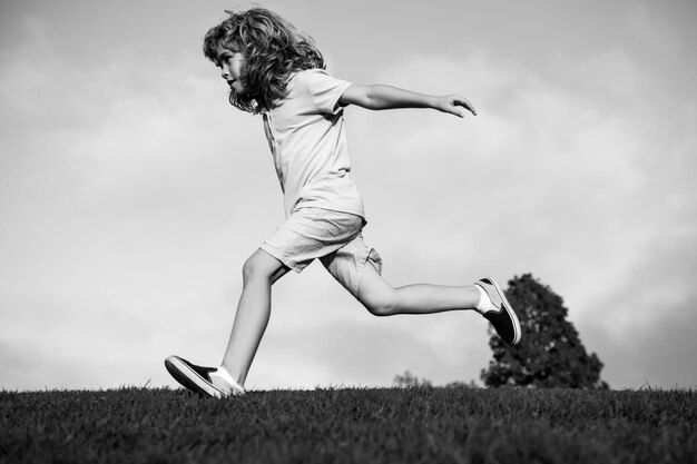 Kindplezier buiten rennen Kind spelen in zomerpark Kleine jongen die op groen vers grasveld loopt
