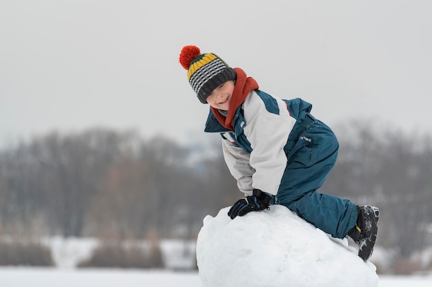 Kindspel in het sneeuwfort. Winterplezier buitenshuis. Jongen klom op stapel sneeuw.