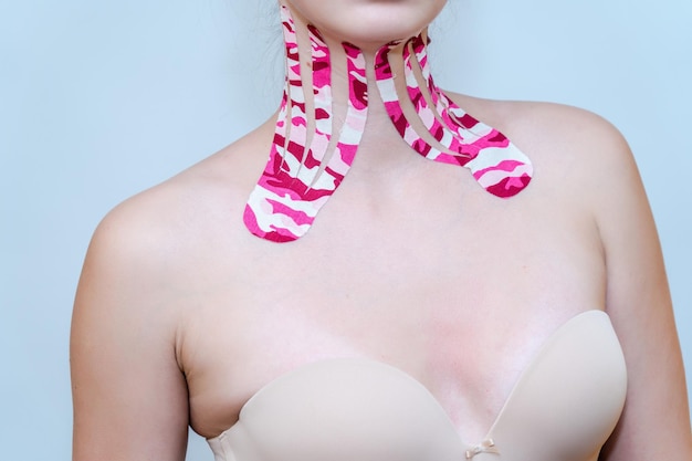 흰색 바탕에 아름다운 젊은 여성의 목에 있는 Kinesio 테이프xA