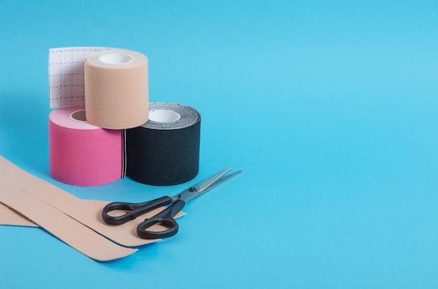 Kinesiological multi-colored tapes for fixing muscles during sports and after injuries on a blue background with a copy space. Kinesiological taping of athletes.