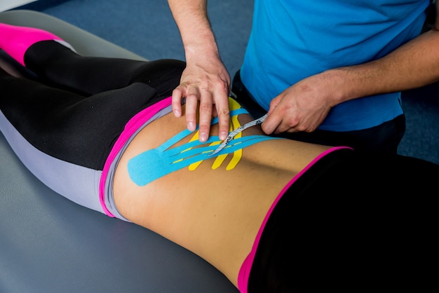 Kinesiotaping. Fysiotherapeut die band toepassen op de rug van de jonge mooie vrouw.