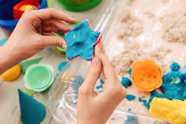 Kinetic sand. children's hands play with multi-colored polymer sand.