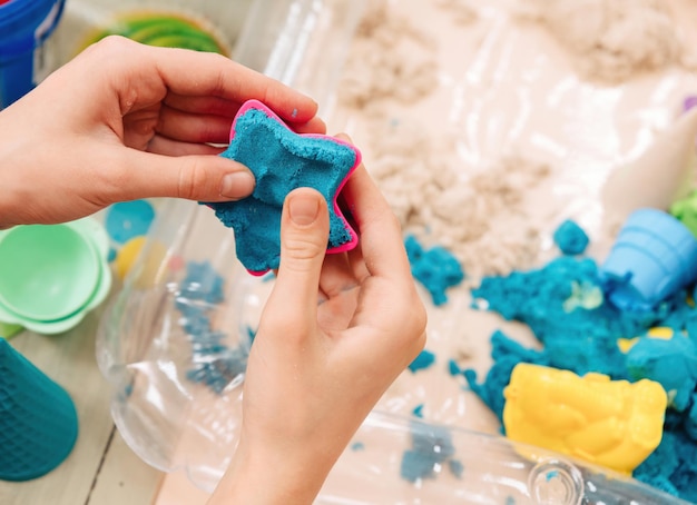 Photo kinetic sand. children's hands play with multi-colored polymer sand.