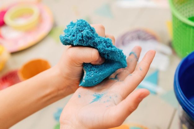Foto sabbia cinetica. le mani dei bambini giocano con la sabbia polimerica multicolore.
