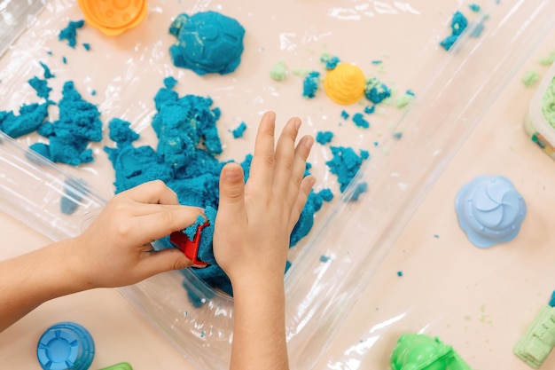 Kinetisch zand. kinderhanden spelen met veelkleurig polymeerzand.