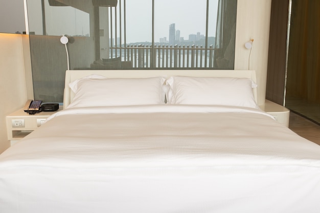 King size bed with white sheets and pillow on bed in hotel room.