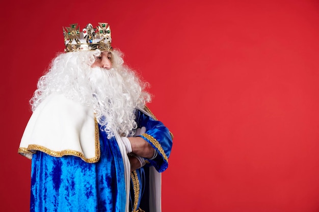 A king with white hair and beard on red background