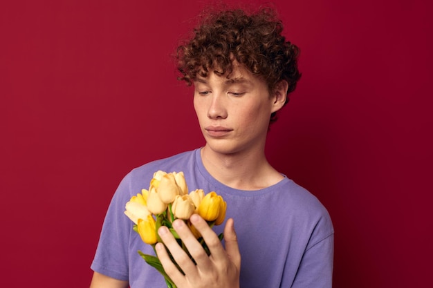 Foto kinky man met een geel boeket bloemen paarse t-shirts rode achtergrond ongewijzigd