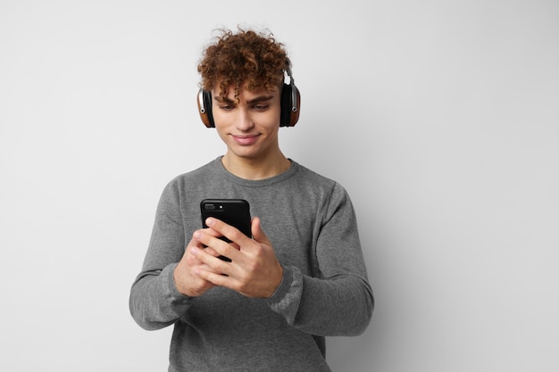 Kinky man met een telefoon in de hand luisteren naar muziek in koptelefoon lichte achtergrond