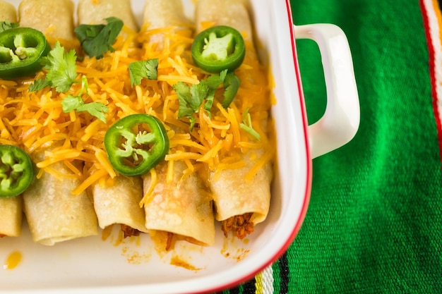 Kip enchiladas met cheddar kaas en saus.