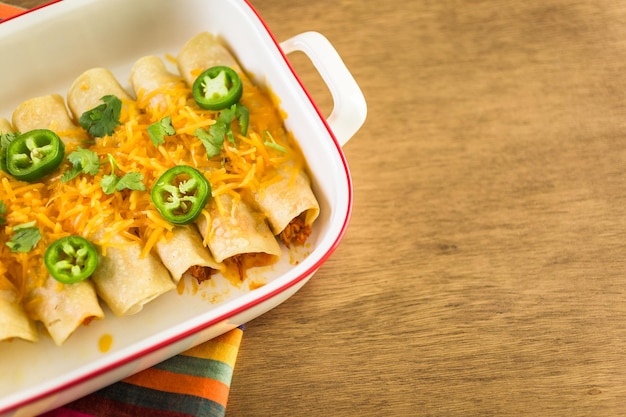 Kip enchiladas met cheddar kaas en saus.