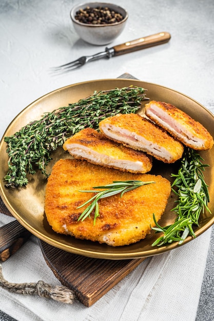 Kip gebakken cordon bleu kotelet met ham en kaas op een bord met kruiden witte achtergrond bovenaanzicht