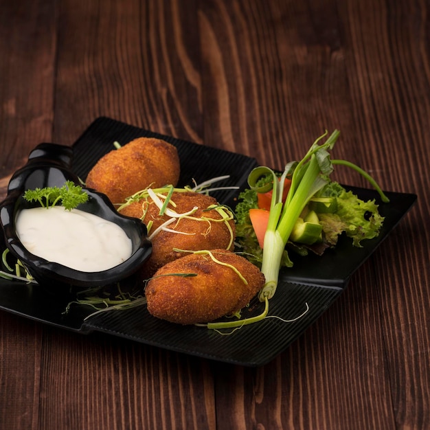 Kip kaas kroket met mayo dip en salade geserveerd in schotel geïsoleerd op tafelblad weergave van voorgerecht