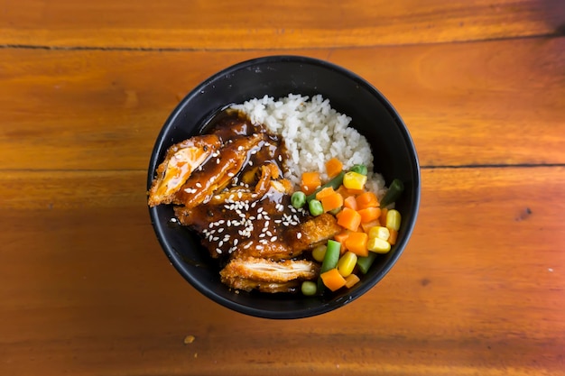 Kip katsu rijstkom met groenten en maïs op houten achtergrond