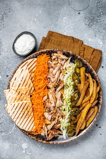 Kip Shoarma Döner kebab op een bord met frietjes, groenten en salade Grijze achtergrond Bovenaanzicht