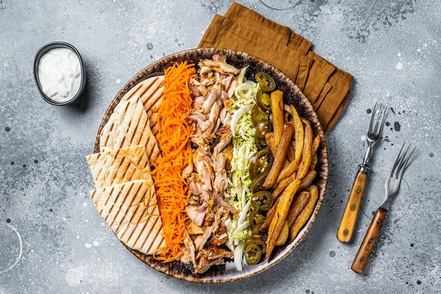 Kip Shoarma Döner kebab op een bord met frietjes, groenten en salade Grijze achtergrond Bovenaanzicht