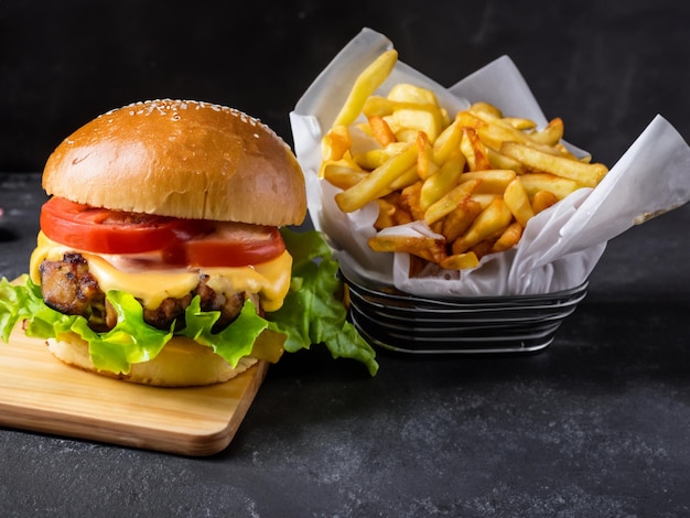 Kipburger met cheddarkaas en friet op donkere achtergrond