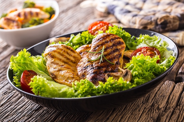 Kipfilet grillen. Geroosterde en gegrilde kipfilet met slasalade, tomaten en champignons.