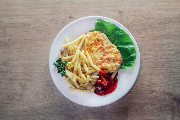 Kipfilet in kaas en frietjes op wit bord