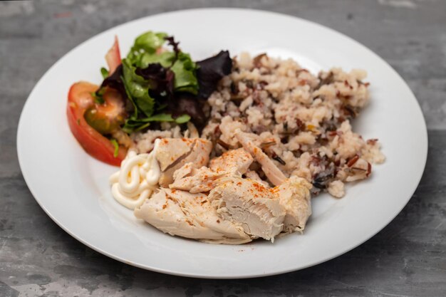 Kipfilet met gekookte rijst en salade op witte plaat