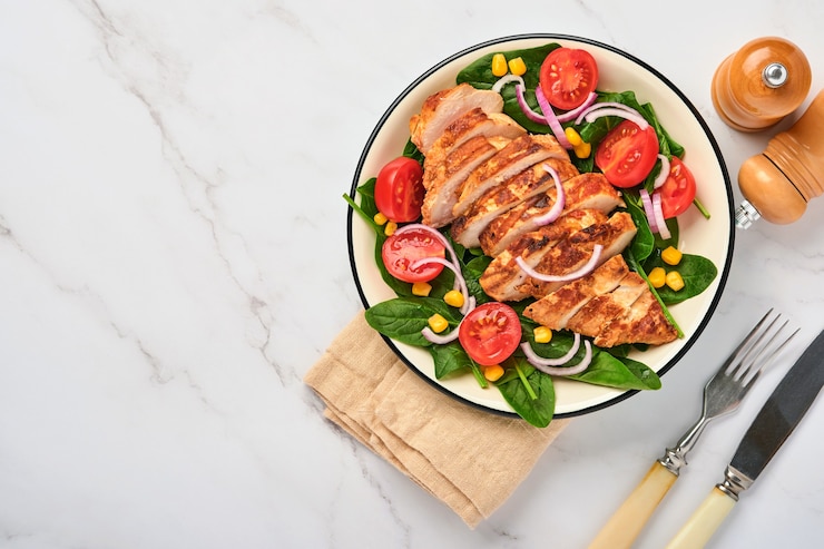 Foto kipfilet met salade spinazie, kerstomaatjes, korenbloem en ui. gezond eten. keto-dieet, dieetlunchconcept. bovenaanzicht op witte achtergrond.