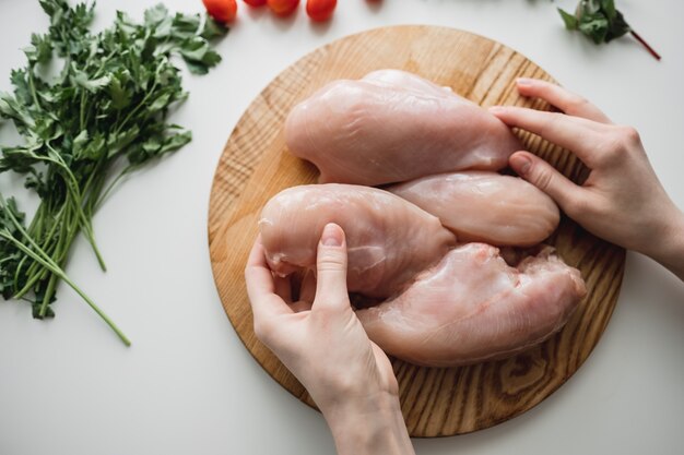 Kipfilet op een houten bord met kruiden