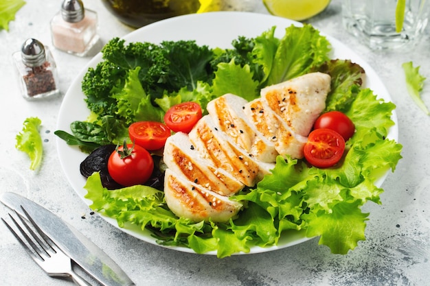 Kipfiletfilet en groentesalade met tomaten en groene bladeren op een lichte achtergrond het concept van gezond voedsel en keto-dieet