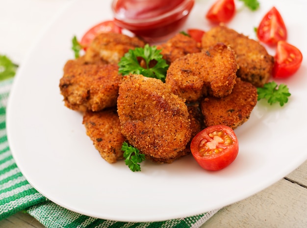 Kipnuggets en saus in plaat op een witte houten tafel