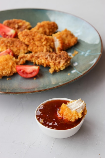 Kipnuggets in maïsbrood op een bord met saus