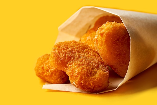 Kipnuggets in papier op een gele achtergrond. Fastfood en fingerfood voor een pub