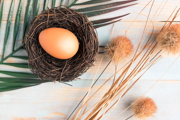 Kippen ei in het nest en decoratieve bloemen bovenkant houten achtergrond