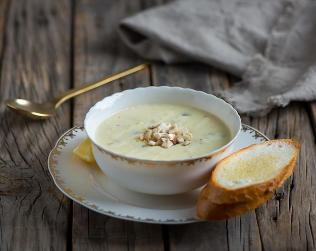 Kippenchampignonsoep met lookbrood geserveerd in een kom geïsoleerd op een houten zijaanzicht als achtergrond