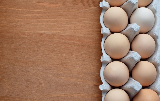 Kippeneieren in een kartonnen doos op een houten tafel Kopieer de ruimte