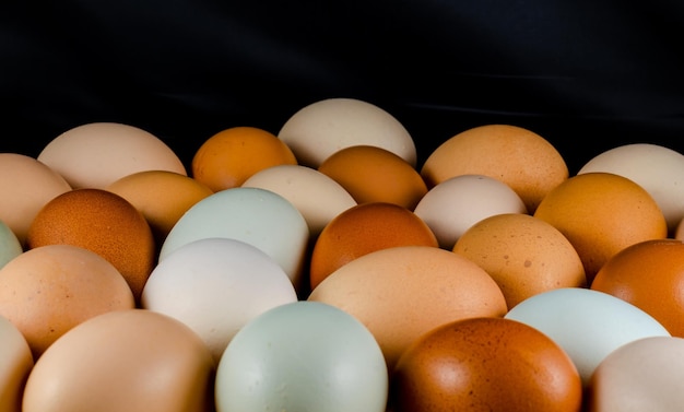 Kippeneieren van verschillende kleuren op tafel op een zwarte achtergrond. Natuurlijk eiwit.